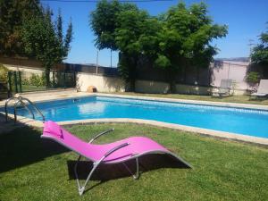 a pink chair sitting in the grass next to a swimming pool at Moradia do Paço - Piscina Privada in Arco de Baúlhe