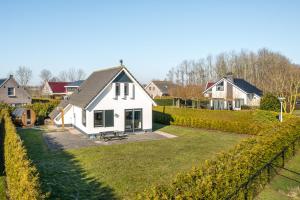 uma casa branca com uma sebe à frente. em The Frisian Beach House met Scandinavische barrel sauna em Tzummarum