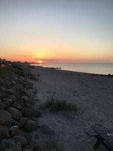 a sunset on a beach with rocks and the ocean at Hasmark beach, nice house close to the beach. in Otterup