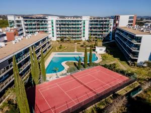 einen Luftblick auf einen Tennisplatz und Gebäude in der Unterkunft Superbe appartement spacieux avec terrasse vue piscine in Vilamoura