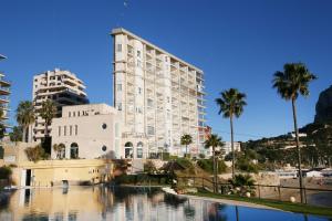 een groot wit gebouw met palmbomen en een waterlichaam bij Apartamento Paradero de Ifach - Costa CarpeDiem in Calpe