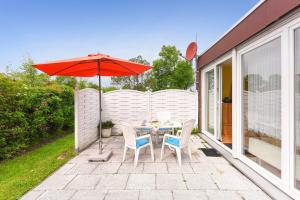 eine Terrasse mit Tisch und Stühlen und einem Sonnenschirm in der Unterkunft Ferienhaus Ingrid in Bensersiel