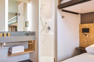 a bathroom with a shower and a bed and a sink at ibis Budget Paris Nord 18ème in Paris