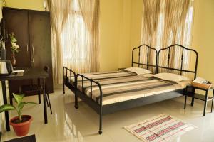 a bedroom with a bed and a table and a desk at GRUHAM SOJOURN HOMESTAY in Guwahati