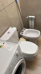 a bathroom with a toilet and a sink and a washing machine at Costanera Aparts in Villa María