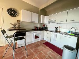 uma cozinha com armários brancos e um relógio na parede em Appartement Jardin exotique em Cap d'Ail