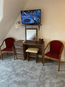 um quarto com uma secretária, uma televisão e 2 cadeiras em Royston Guest House Inverness em Inverness