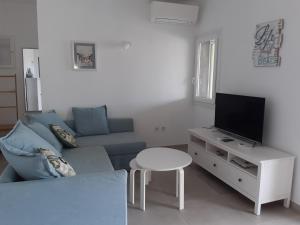 a living room with a blue couch and a tv at Villa Ligia Beach in Koundouros