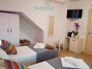 Sala de estar con 2 camas y mesa en Affittacamere Mariposa, en Dorgali