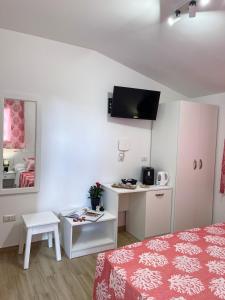 een slaapkamer met een bed en een bureau met een televisie bij Affittacamere Mariposa in Dorgali