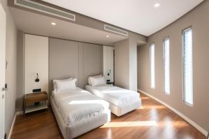 two beds in a room with wood floors and windows at Yacht Hotel in Vlorë