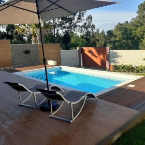 a swimming pool with two chairs and an umbrella at Leiria Village casa bungalow in Leiria