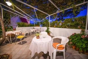 a patio with white tables and chairs and plants at Hotel Europa in Ischia