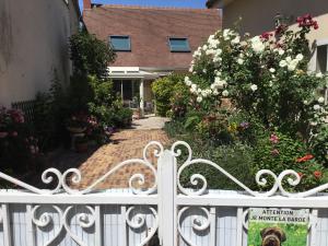 een wit hek voor een huis met bloemen bij Au Bon Gite - Studio in Arromanches-les-Bains