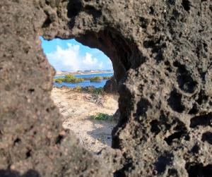 a hole in a rock with a view of the ocean at COMPLEJO PONTA das BRILLES DUPLEX in Nísia Floresta