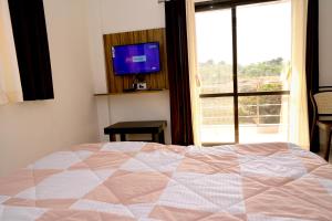 um quarto com uma cama, uma televisão e uma janela em ELITE HOME em Mahabaleshwar