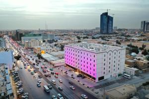 um edifício rosa numa rua da cidade com trânsito em Hayat Al Riyadh Washam Hotel em Riade