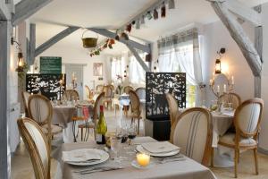 Soings-en-SologneにあるLogis Hôtel Restaurant LE VIEUX FUSILの白いテーブルと椅子のあるレストラン、