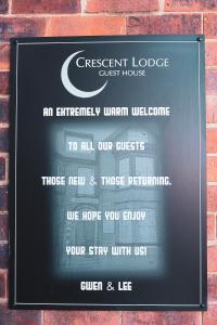 un cartel para una casa de huéspedes en una pared de ladrillo en Crescent Lodge Guest House en Whitby