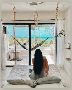 a woman sitting on a bed in front of a window at LunArena Boutique Beach Hotel Yucatán Mexico in El Cuyo