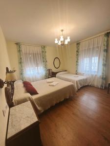 - une chambre avec 2 lits et un lustre dans l'établissement Casa Rural la Abuela Amelia, à Garcinarro