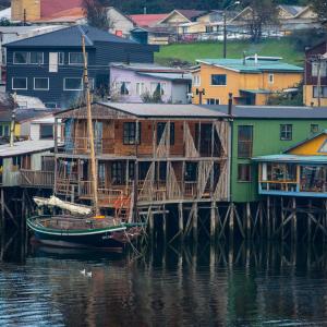 eine Gruppe von Häusern und ein Boot auf dem Wasser in der Unterkunft Hostal Palafito Waiwen in Castro