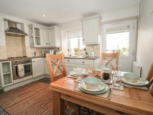 a kitchen with a wooden table with plates and bowls on it at Jasmine Cottage in Axminster