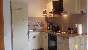 uma pequena cozinha com armários brancos e um fogão em Haus Sonja em Adenau