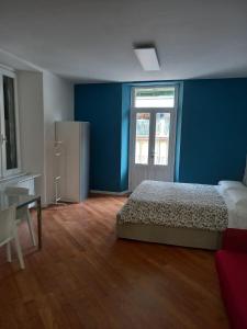 1 dormitorio con paredes azules, 1 cama y escritorio en Suite Apartment San Lazzaro, en Bérgamo