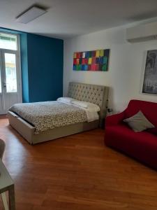 a bedroom with a bed and a red couch at Suite Apartment San Lazzaro in Bergamo