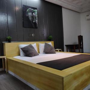 Un dormitorio con una gran cama de madera con almohadas en La Maison de Kouadio en Abiyán