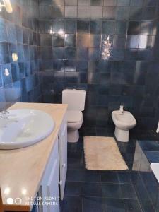 ein blau gefliestes Bad mit 2 WCs und einem Waschbecken in der Unterkunft City House in Vila Real