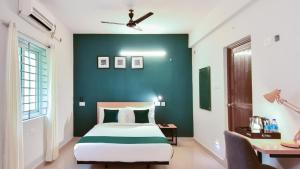 a bedroom with a bed and a green wall at Crayons Hotel in Chennai