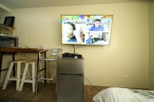 a television hanging on a wall in a kitchen at A2J Executive Studio Suite Near Enchanted Kingdom in Silang