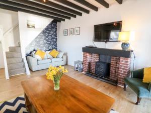 a living room with a fireplace and a tv at Malltraeth Cottage in Bodorgan