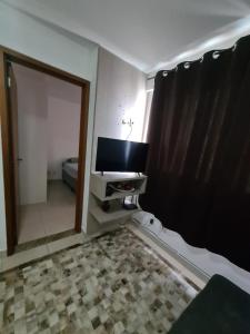 a bathroom with a mirror and a tv in a room at Apt encantador: piscina, academia, tela proteção in Taguatinga
