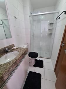 een witte badkamer met een wastafel en een douche bij Apt encantador: piscina, academia, tela proteção in Taguatinga