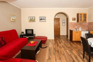 a living room with a red couch and a kitchen at Apartments Izvor in Vrdnik