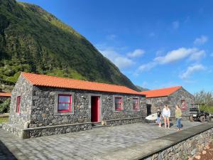a small stone building with a mountain in the background at Kuanza Nature Experience, Fajã do Belo in Fajã da Caldeira de Santo Cristo