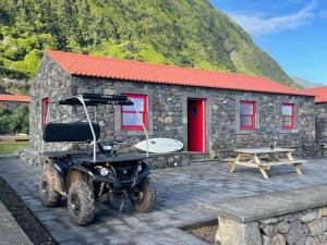 a golf cart parked in front of a stone building at Kuanza Nature Experience, Fajã do Belo in Fajã da Caldeira de Santo Cristo