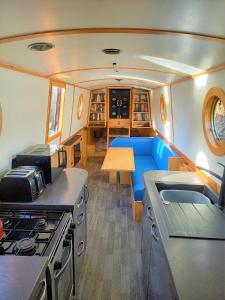 a kitchen with a stove and a blue couch at Smoke (Rowington Narrowboats) in Warwick