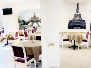un restaurante con mesas y sillas y la torre Eiffel en Hôtel D'orsay, en Orsay
