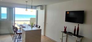 eine Küche mit einem Tisch mit Stühlen und einem Fernseher an der Wand in der Unterkunft Belle Vue Mer Canet Plage accès piscine couverte et chauffée in Canet-en-Roussillon