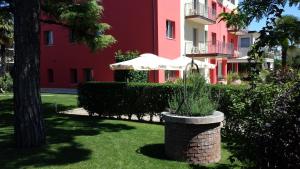 ヴェローナにあるヴェローナ ラ グロッタの傘を芝生に置いたピンクの建物