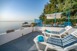 une terrasse avec 2 chaises et une table à côté de l'eau dans l'établissement Agistri By The Sea, à Perama