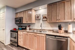 cocina con armarios de madera y fregadero de acero inoxidable en Quiet and Serene Condo in Branson en Branson