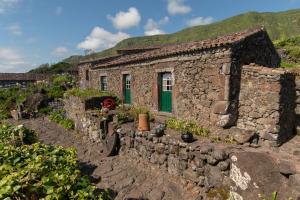 an old stone house with a green door at Aldeia da Cuada in Faja Grande
