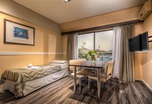 ブエノスアイレスにあるUp Viamonte Hotelのベッド、テーブル、窓が備わる客室です。
