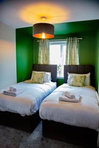 duas camas num quarto com paredes verdes em The Marine - Balcony - Beach View - Coorie Doon Apartments em Ayr