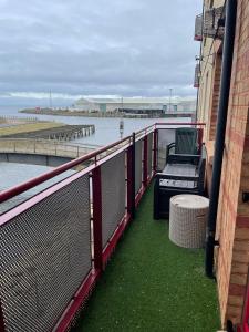 a balcony with a bench next to the water at The Marine - Balcony - Beach View - Coorie Doon Apartments in Ayr
